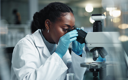 Wissenschaftler, der Mikroskop verwendet Wissenschaftler tragen Handschuhe und schauen durch ein Mikroskop in einem Labor.
