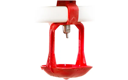 Rote Geflügeltränke mit Nippelsystem an einem weißen Rohr.